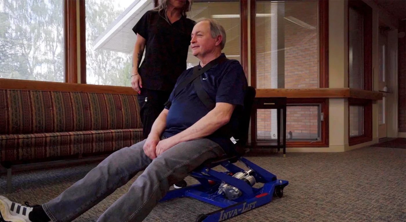 A caregiver assisting a resident seated in the Inva-Lift Pro 500