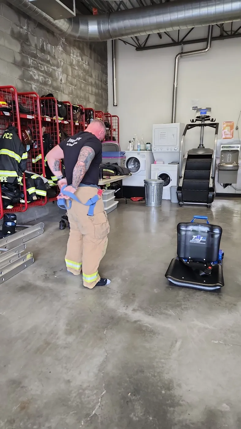 A firefighter gearing up in the station bay with the Inva-Lift Pro 500 beside him
