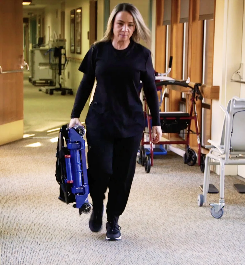 Jennifer carrying the folded Inva-Lift Pro 500 down a care facility hallway