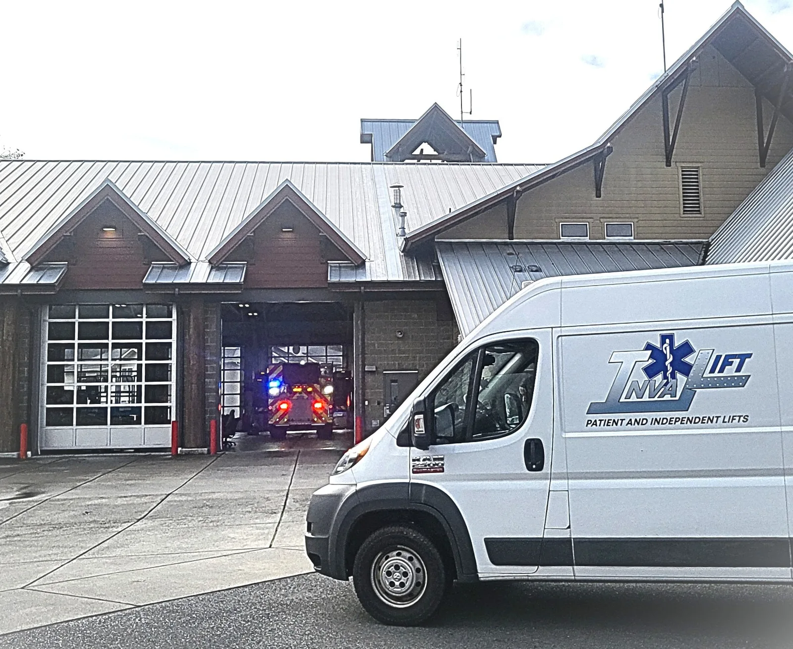 An Inva-Lift van delivering to a fire station, an engine in the open bay